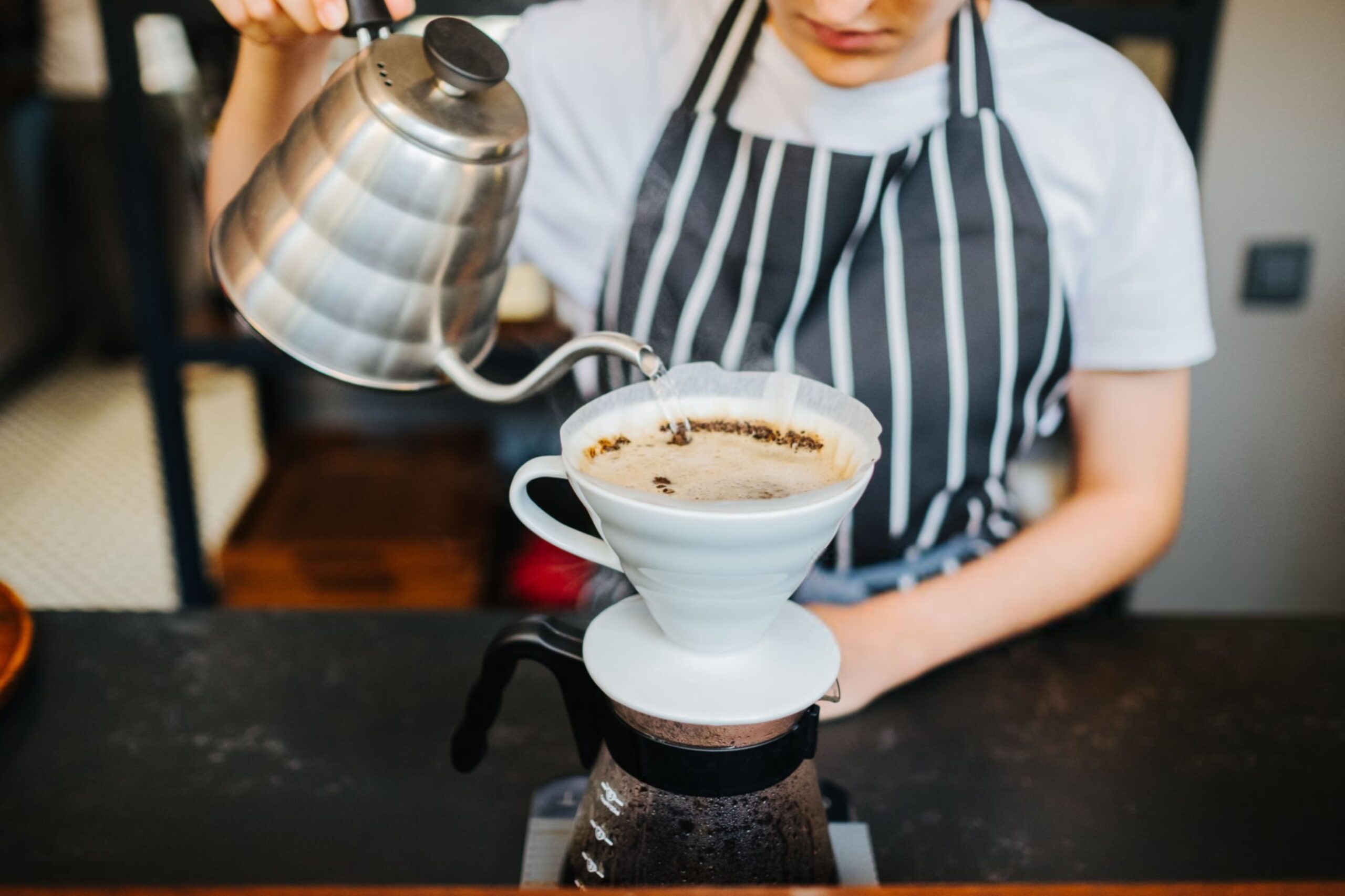 باریستا در حال دم کردن قهوه به روش پور اور با کمکس و کتری دهانه باریک