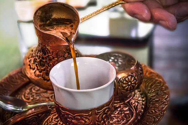 جذوه مسی در حال تهیه قهوه ترک روی حرارت، کنار فنجان سنتی در استانبول