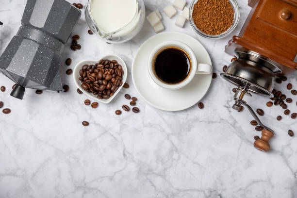 دانههای تازه قهوه کنار آسیاب دستی و ابزار دمآوری خانگی روی میز چوبی